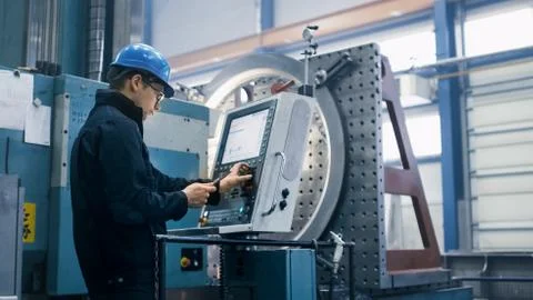 Factory worker is programming a CNC milling machine with a tablet computer. Foto stock