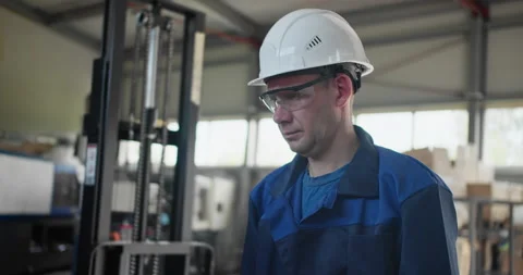 Factory worker in protective helmet and safety glasses during production shift Stock Footage 327133534