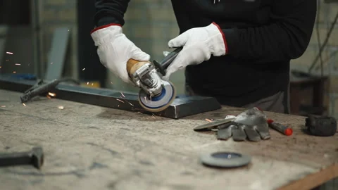 Factory worker in protective uniform, gloves and welding helmet using grinding Stock Footage 262575060
