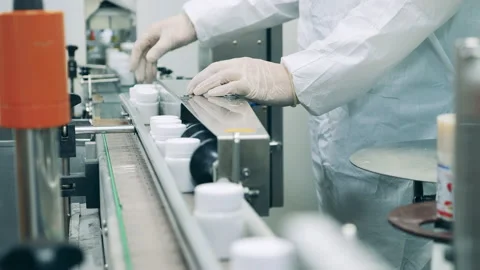 Factory worker is regulating a conveyor with pill tubs Stock Footage 160417552