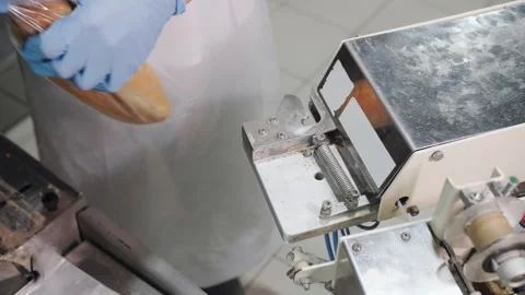 Factory Worker Sealing Bread Loaf In Plastic Wrap. Bakery production. Stock Footage 321735509