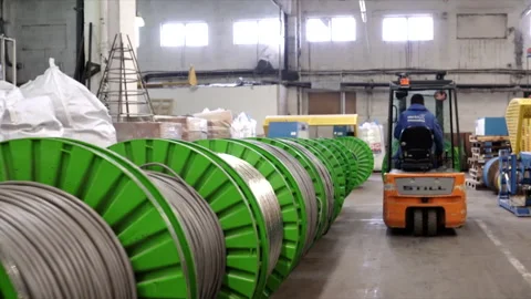 A factory worker, seen from behind with the forklift that carries large rollers  스톡 동영상 153179891