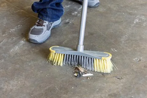 Factory Worker Sweeping Debris from Concrete Floor in Warehouse Stock-Fotos