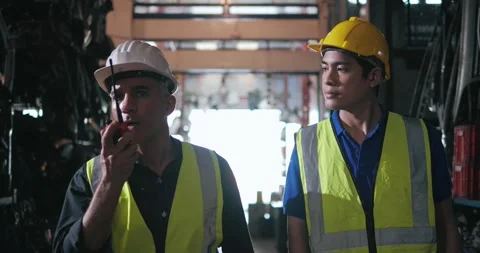 Factory worker talking on portable radio while walking inspecting machinery part Stock Footage 156387342
