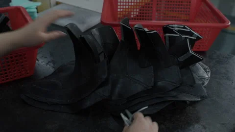 Factory Worker Trims Black Shoe Uppers by Hand at Industrial Work Table Stock Footage 341667418