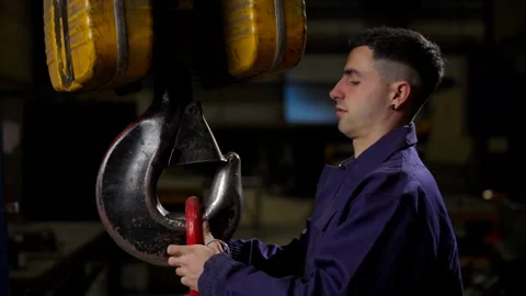 Factory worker using a crane to lift chains Stock Footage 266950877