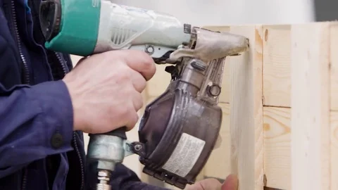 Factory worker using nail gun on wooden surface. Industrial setting Stock Footage 81505114