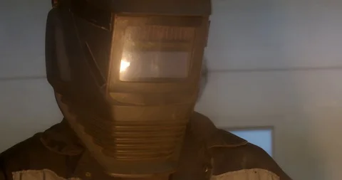 Factory worker wearing a protective welding helmet as torch burns Stock Footage 120618797