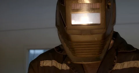 Factory worker wearing a protective welding helmet as torch burns Stock Footage 120618818