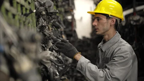 A factory worker wearing a safety helmet inspecting used car parts Video stock 319844361