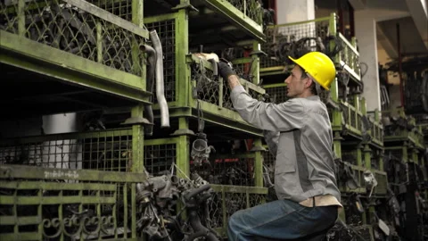 A factory worker wearing a safety helmet inspecting used car parts Stock Footage 319844397