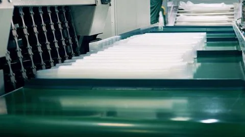 Factory worker wrapping many plastic cups Photos