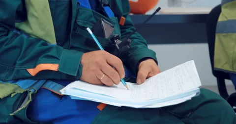 Factory worker writes down notes with a pencil in a notebook that are important  Stock Footage 147634089
