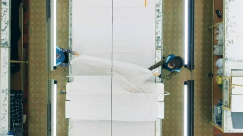Factory workers are flattening out textile sheet in a top view Video stock 147238906