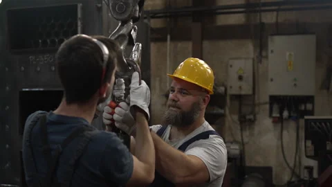 Factory workers collaborating on a crane hook Stock Footage 334723205