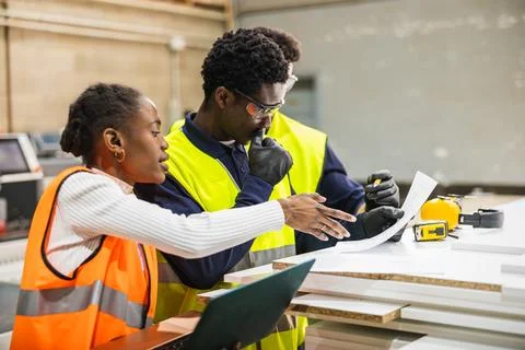 Factory workers collaborating on project blueprints at lumberyard Foto stock