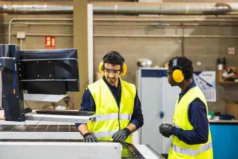 Factory workers operating cnc machine in lumberyard Stock Photos