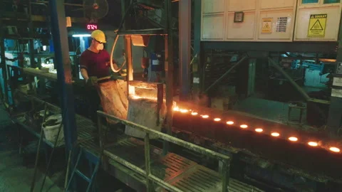 Factory workers in protective gear pour molten metal into mold Stock Footage 304377121