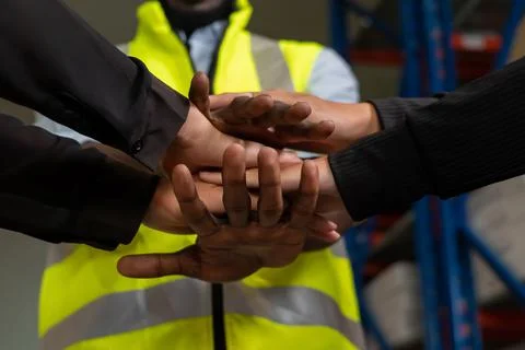 Factory workers stacking hands together in warehouse or storehouse Stock Photos