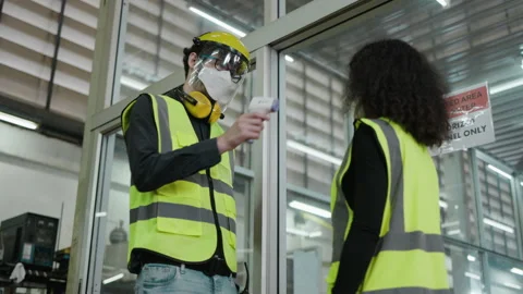 Factory workers use machine to check body temperature for construction workers.  Stock Footage 157640711