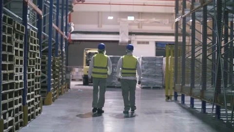 Factory workers walk through large warehouse filled with crates. Stock Footage 157397976