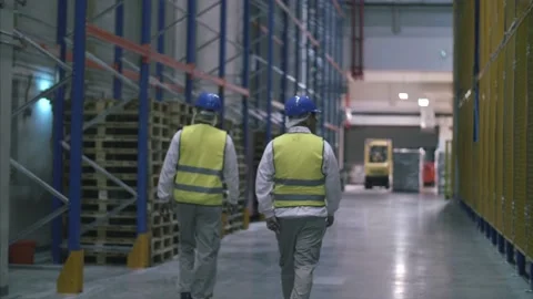 Factory workers walk through large warehouse filled with crates. Stock Footage 157398429