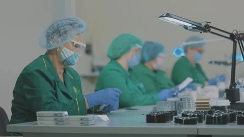 Factory workers wearing masks. Work during a pandemic. Women pack pills in a 库存影片 218963359