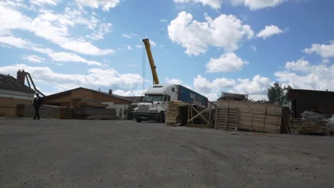 Factory yard with piles of boards and crane under cloudy sky Stock Footage 140672544