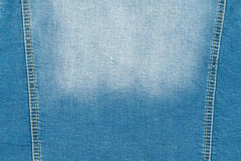 Faded blue jeans texture with stitching. Close up of classic denim cloth Фото