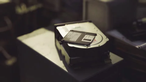 Faded hard drives and floppy disk on aged work surface with warm lighting Stock Footage 331397559