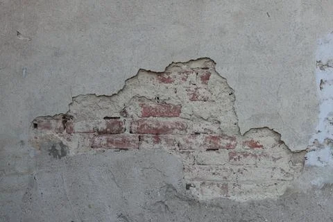 Faded plaster of a house with red bricks in the base Stock Photos