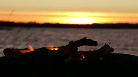 Fading campfire at a windy sunset lake Stock Footage 44518087