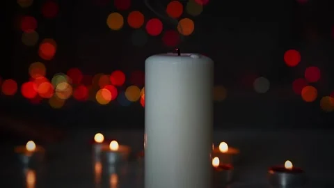 Fading flame of  large candle standing in dark room among small flames. Stock Footage 148138993