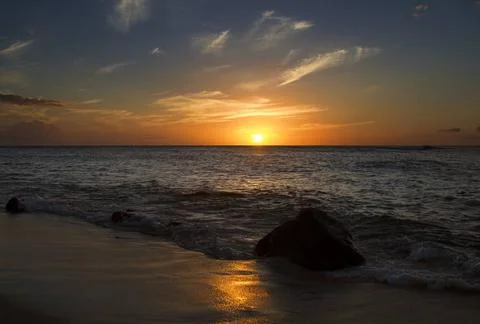 Fading light sunset over the calm pacific ocean with a boulder being pound... Fotos Stock