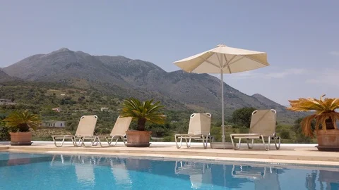 Fading Out Tilt Shot of Sun Loungers &amp; Umbrellas Adjacent to Luxury Pool Vidéo 109616911
