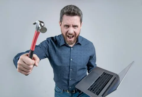 Failed to complete a task. Angry man shout holding hammer and laptop. Computer Stock Photos