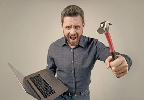 Failed to complete a task. Angry man shout holding hammer and laptop. Computer Foto stock