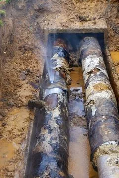 Failed repair of leaking heating pipe with clamp unable to stop hot water jet 写真素材