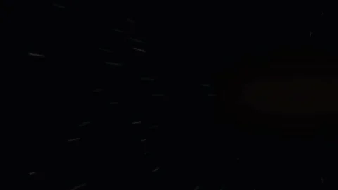 Faint glowing particles floating in a dark void, creating subtle streaks of.. Stock Footage 345760523