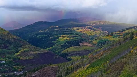 Faint rainbow below low clouds above autumn Vail, Colorado mountains, aerial Stock Footage 347944452