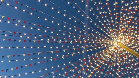 Fair decorations, flags and light bulbs in the sky in the evening, bottom vie Stock Footage 253576519