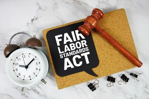 Fair Labor Standards Act text on speech bubble with alarm clock and wooden .. Stock Photos