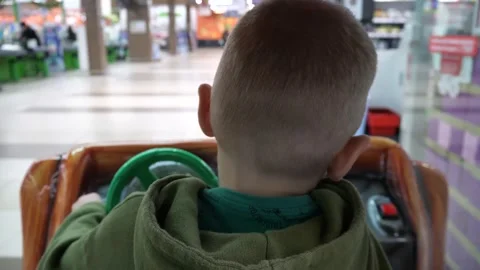 A fair-skinned boy of about 4-5 years old sits in a slot machine car Stock Footage 300378550