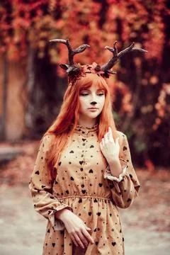 Fairy woman with deer horns in autumn forest. Face painting. Stock Photos