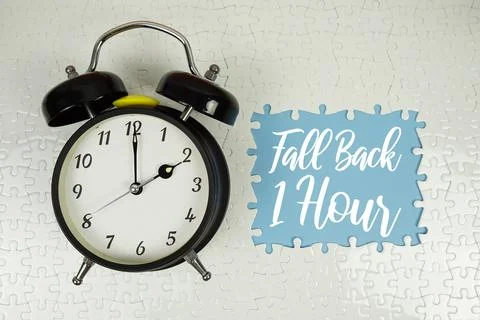 Fall Back 1 Hour text with alarm clock on blue background Stock Photos