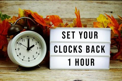 Fall Back Set your clocks back 1 hour text with alarm clock and maple leaf .. Stock Photos