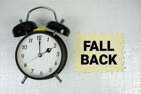 Fall Back text with alarm clock on yellow background Stock Photos