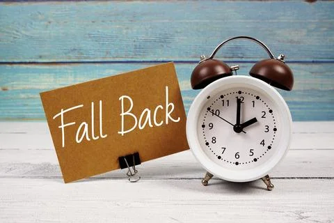 Fall Back  text written on paper card with alarm clock on wooden background Stock Photos