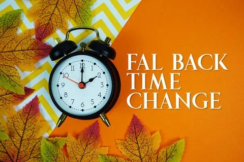 Fall Back Time Change with alarm clock and maple leaf decorated on orange b.. Stock Photos