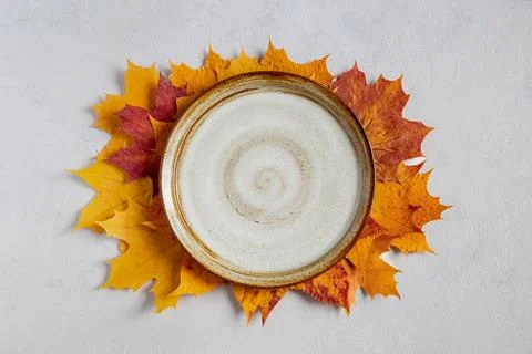 Fall background with empty white plate on yellow autumn maple leaves  Stock Photos